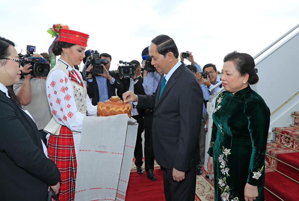 身穿传统服饰的白俄罗斯姑娘按照当地迎接最尊贵客人的礼节向陈大光主席和夫人献上象征热情友好的面包和盐。（图片来源：越通社）