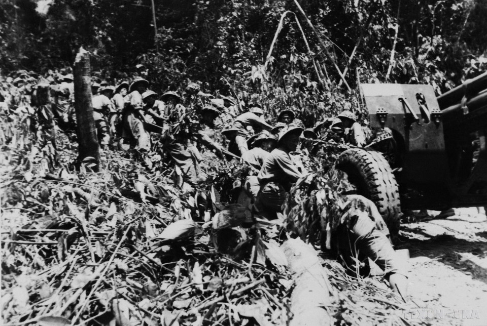 奠边府战役期间，越南人民军炮兵战士高举迎难而上旗帜，克服种种困难将重达数吨的大炮拉上战场。图自 越通社