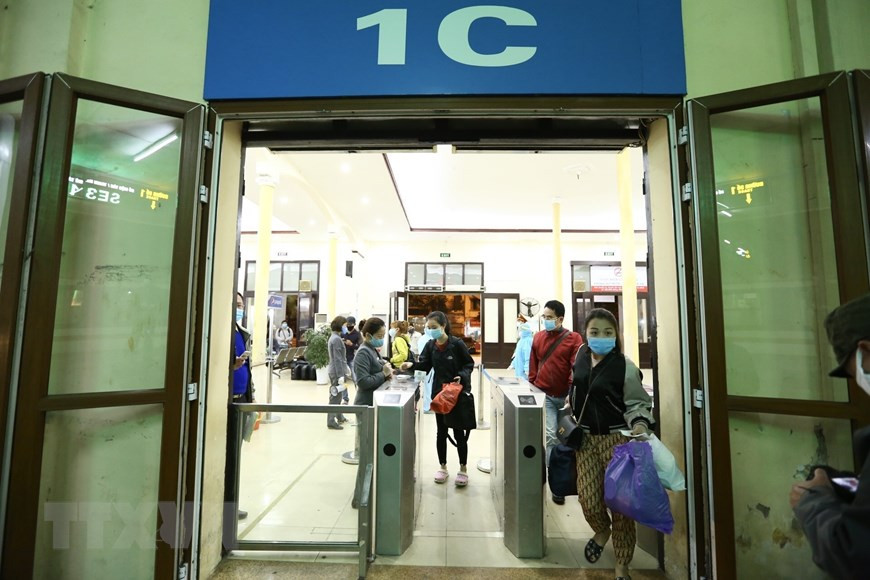 乘客通过检票口，准备上火车。（图自越通社）