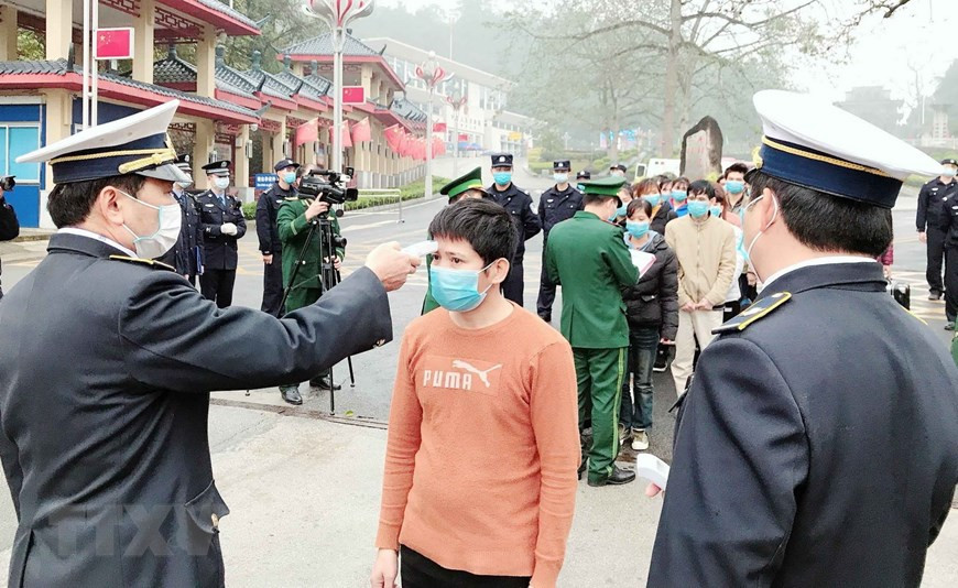 在各国际口岸，在办理入境越南的手续之前，医务人员给旅客测量体温。（图自越通社）