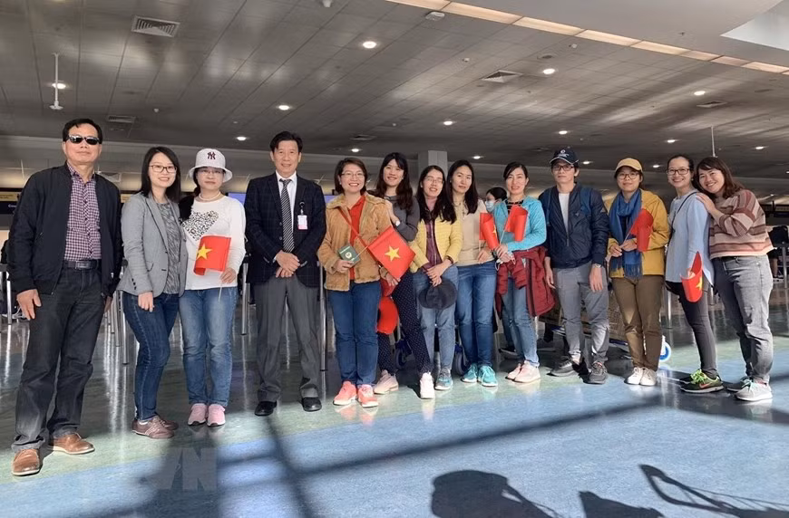 在奥克兰机场，越南驻新西兰大使谢文通与即将飞往澳大利亚悉尼机场转机回国的越南公民合影。（图自越通社）