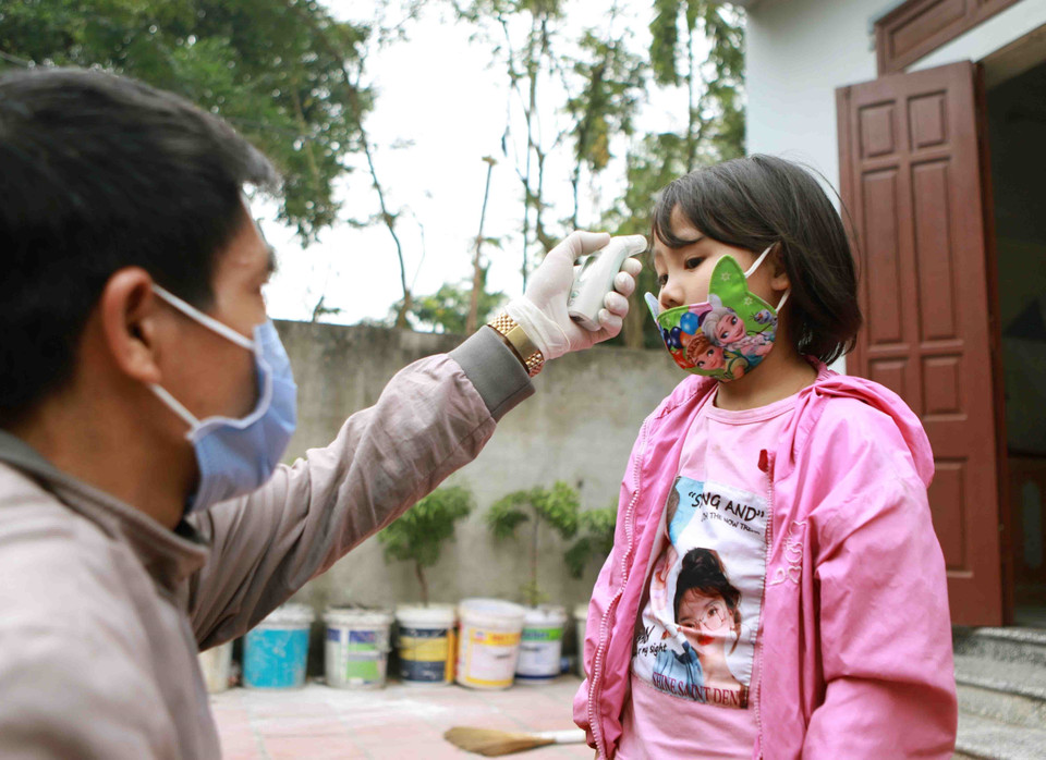 医务人员为梁沟村的小孩测量体温。（越通社记者黄孟雄 摄）