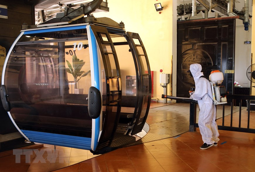 巴拿山旅游区对缆车进行喷洒消毒剂，以确保游客的健康安全。图自越通社