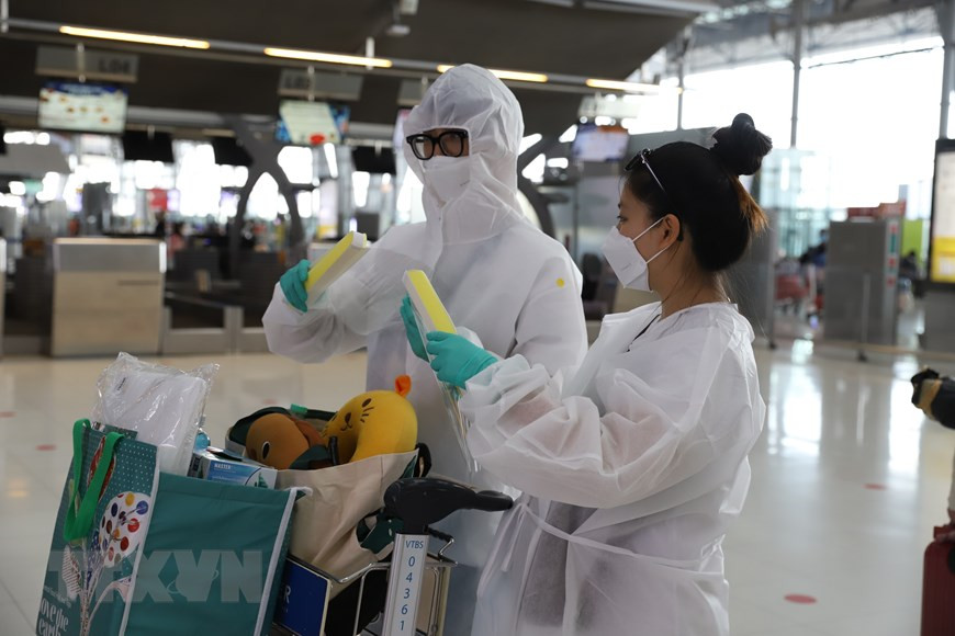 乘客都戴上防疫口罩和穿上防疫服。图自越通社