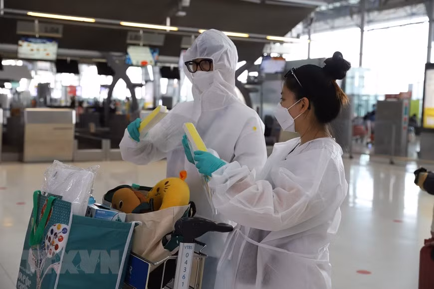 乘客都戴上防疫口罩和穿上防疫服。图自越通社