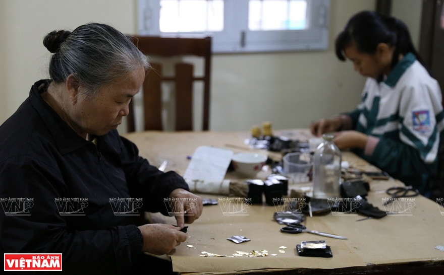 男女老少参加贴金工作。图自越通社