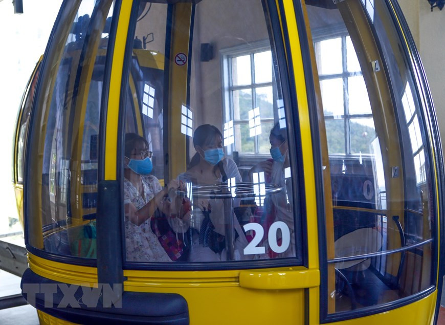 缆车上仍保持一定的距离，游客必须要佩戴口罩。图自越通社