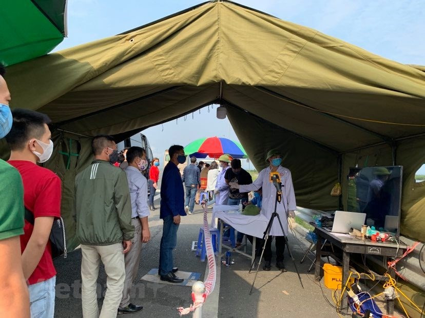 人民都要在检查点停留，测量体温。图自越通社