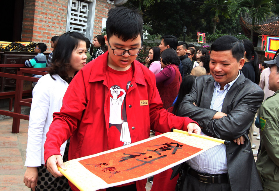 年轻游客请图翁替人写字，希望在新一年里安康、旺盛。越通社记者 国庆 摄