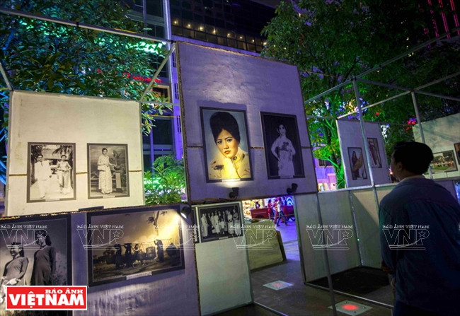 游客在阮惠步行街欣赏“世代传承的越南长衫之美”摄影作品。（图片来源：越南画报）