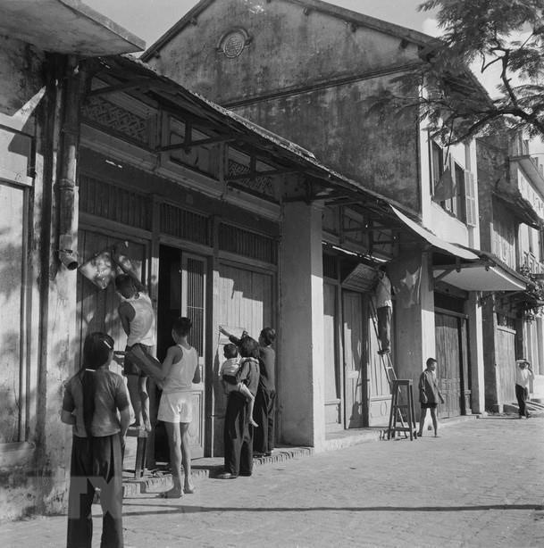 1954年10月10日早晨， 河内居民在自己的家们前悬挂国旗、标语等喜迎解放军凯旋归来。图自 越通社