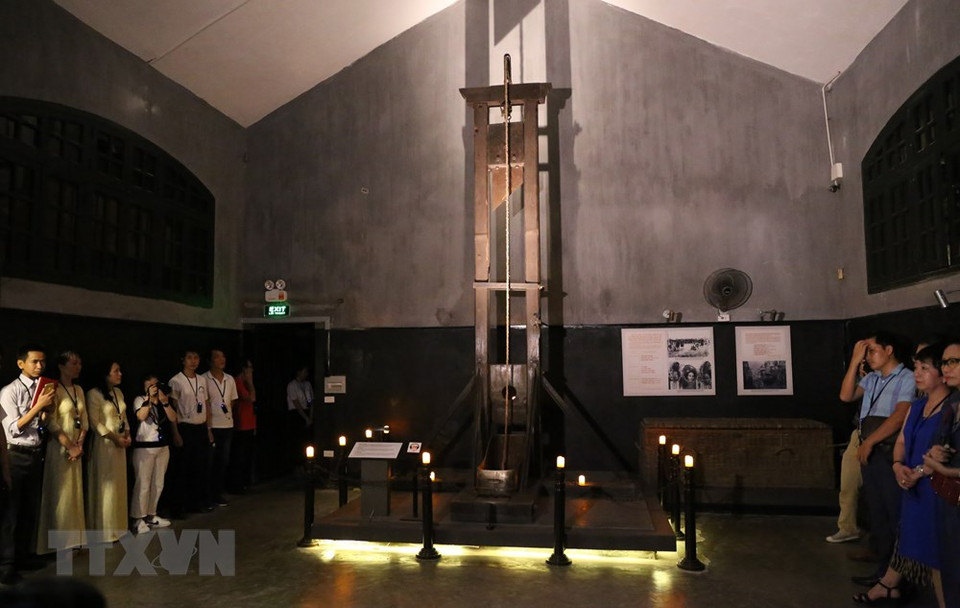 火炉监狱遗迹区讲解员向游客介绍有关该监狱里的断头台。越通社记者 黄敬 摄