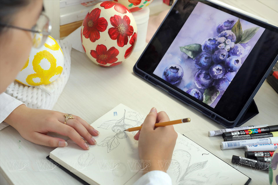 阮张煌珠先在纸上打稿，后在蛋壳上画画。图自越通社/《越南画报》