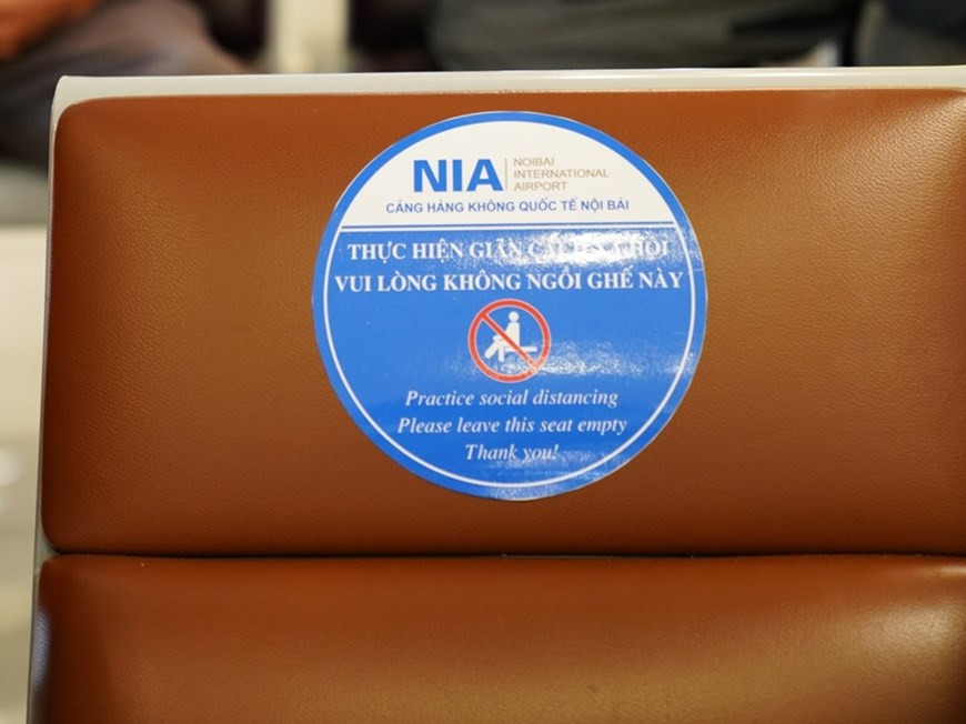 以防止新冠肺炎疫情扩散蔓延。机场在显示屏幕上播放有关新冠肺炎疫情防控措施的视频，引导旅客各项预防疫情的措施。机场候机楼里两个椅子之间隔一个，确保旅客安全。图为机场候机楼里椅子上贴着不允许使用的提示贴，提醒旅客保持一定的距离，以防止新冠肺炎疫情扩散蔓延。越通社记者 潘功 摄