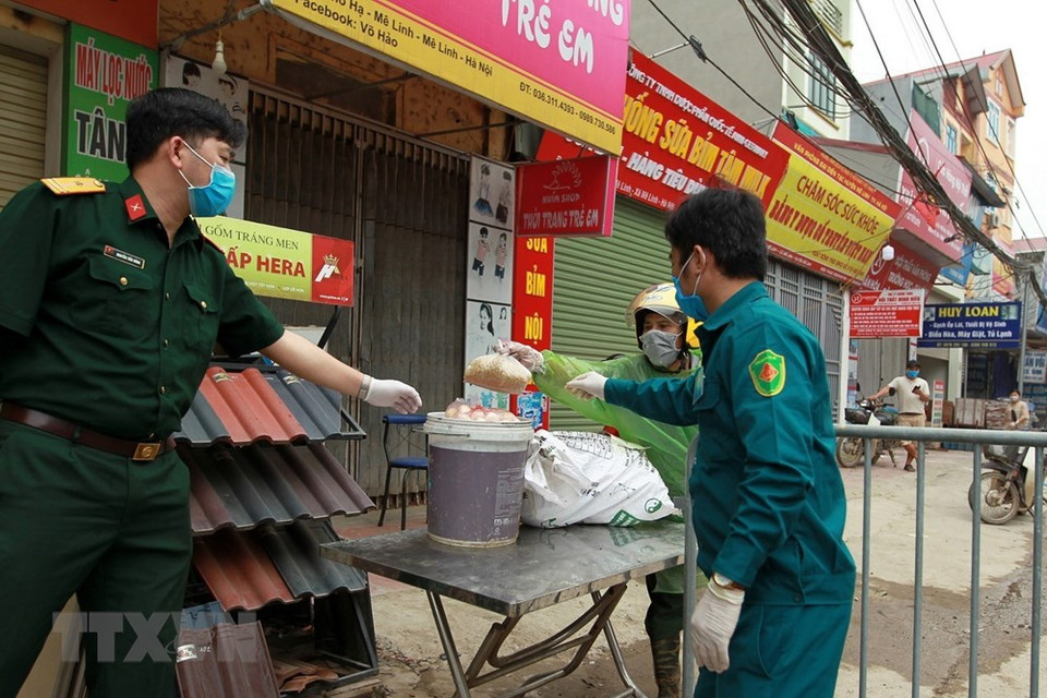 夏雷村隔离区居民按照规定接受生活必需品。 越通社记者明决 摄