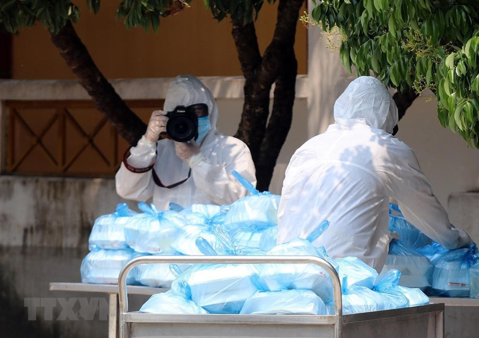 越通社奠边省分社记者 潘俊英在奠边省军事学校隔离区进行报道。记者都穿防护服。图自越通社