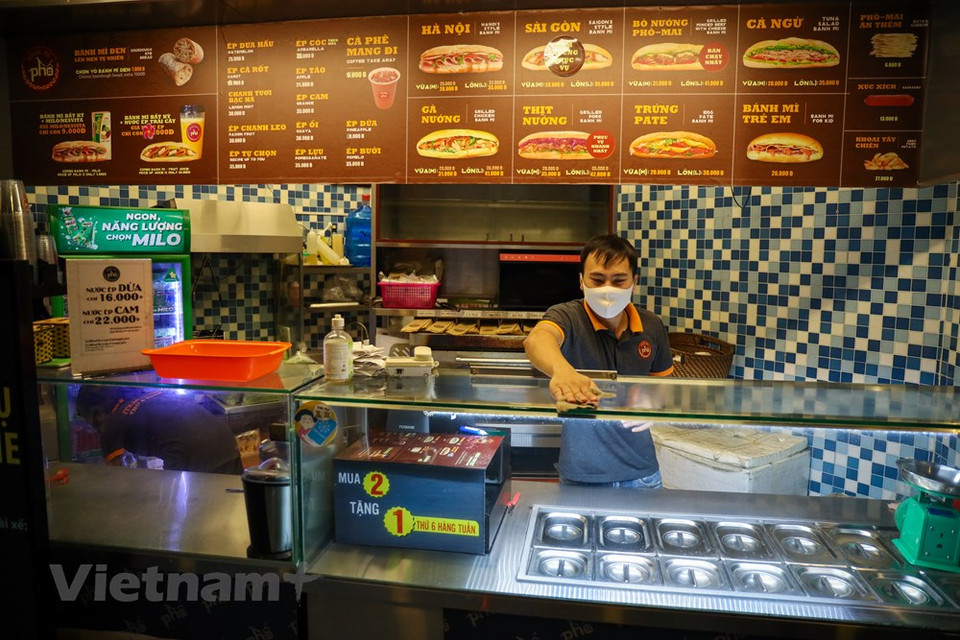  社交距离措施放宽后，人们逐步进入“新常态”，做了“与新冠肺炎疫情共处”的心理准备。人们习惯出门时佩戴口罩，勤洗手，保持安全距离等。4月23日正式放宽社会距离措施的第一天，这家早餐店早上6点就开门迎客。图为：服务员打扫店里卫生，进行消毒，准备迎客。Vietnam+记者 明山 摄