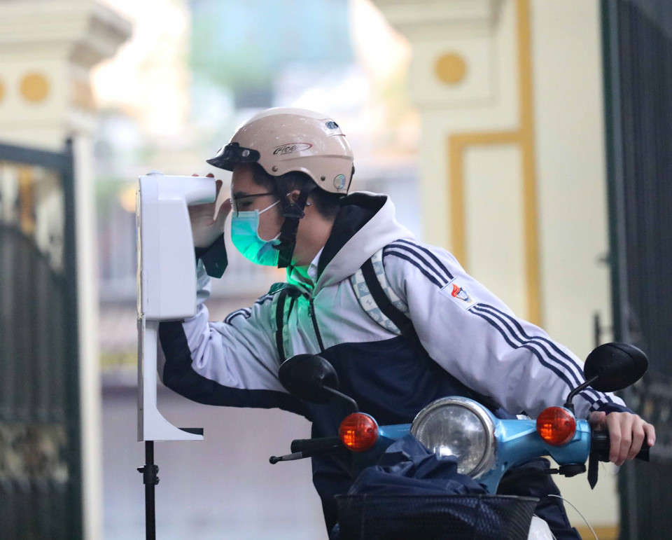 河内市越德高中学校三年级学生进入学校上课之前，教师们给学生们测量体温和洗手杀菌。图自越通社