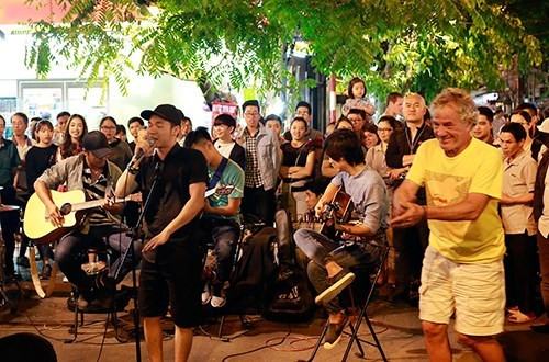 外国游客开心地与街头音乐队一起表演。（图片来源：《人民军队报》）