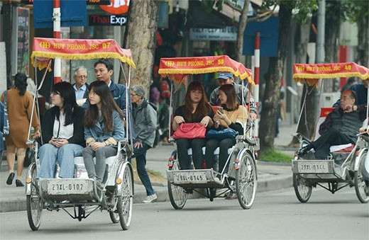 年轻人喜欢坐在三轮车观看河内古街。（图片来源：越南《人民军队报》）