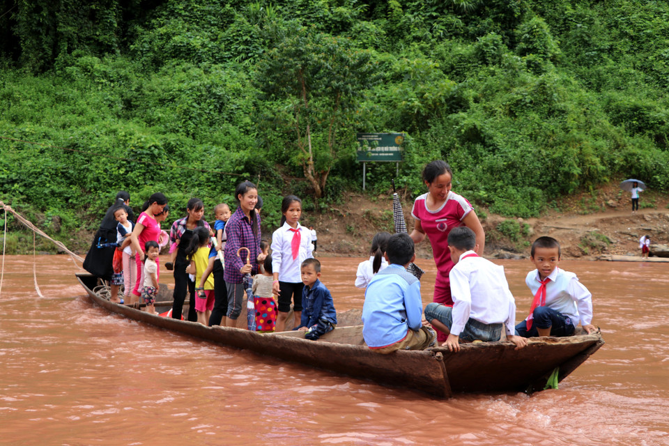 师生们要坐船跨过跨过水流湍急的两条小溪赶来参加开学典礼。越通社记者 越皇 摄