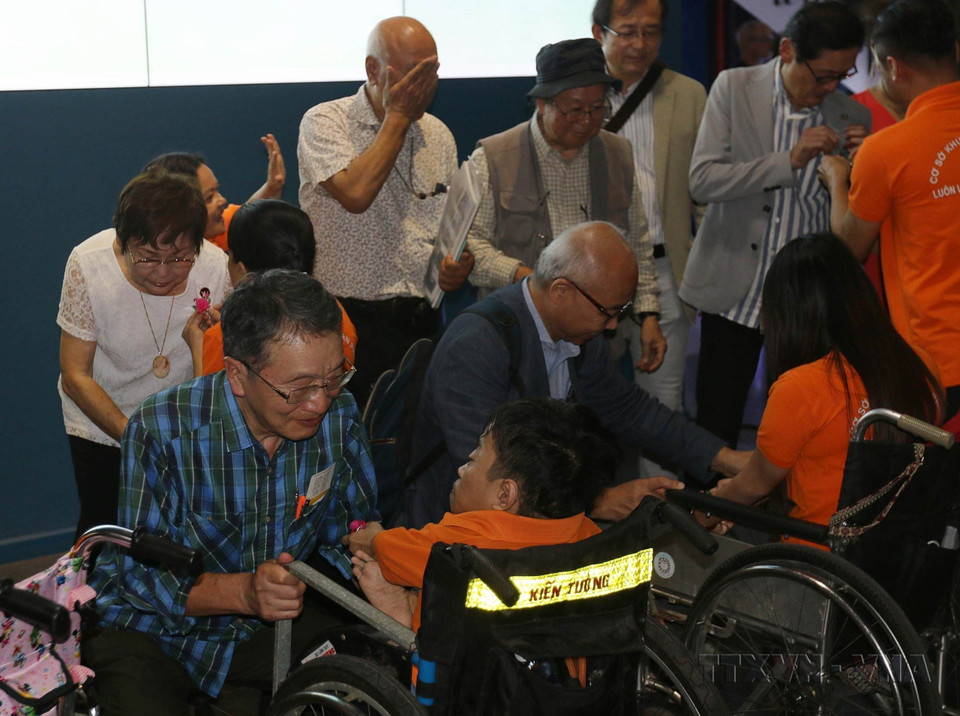 和平村儿童、橙毒剂受害者向参加战争受害者图片展的日本代表赠送纪念品。图自越通社