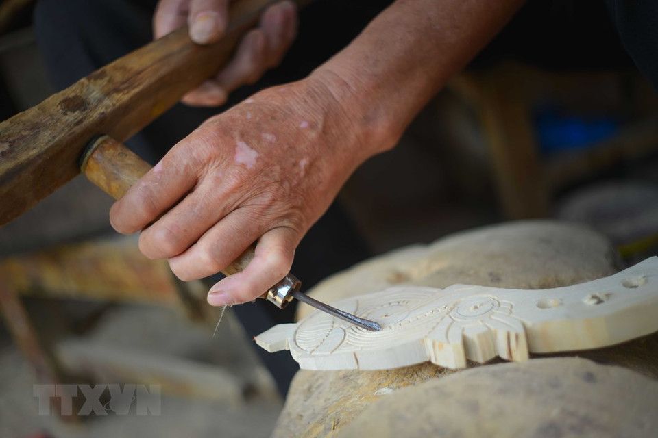 琴杆上的花纹由艺人们仔细地雕刻。越通社记者 越山 摄