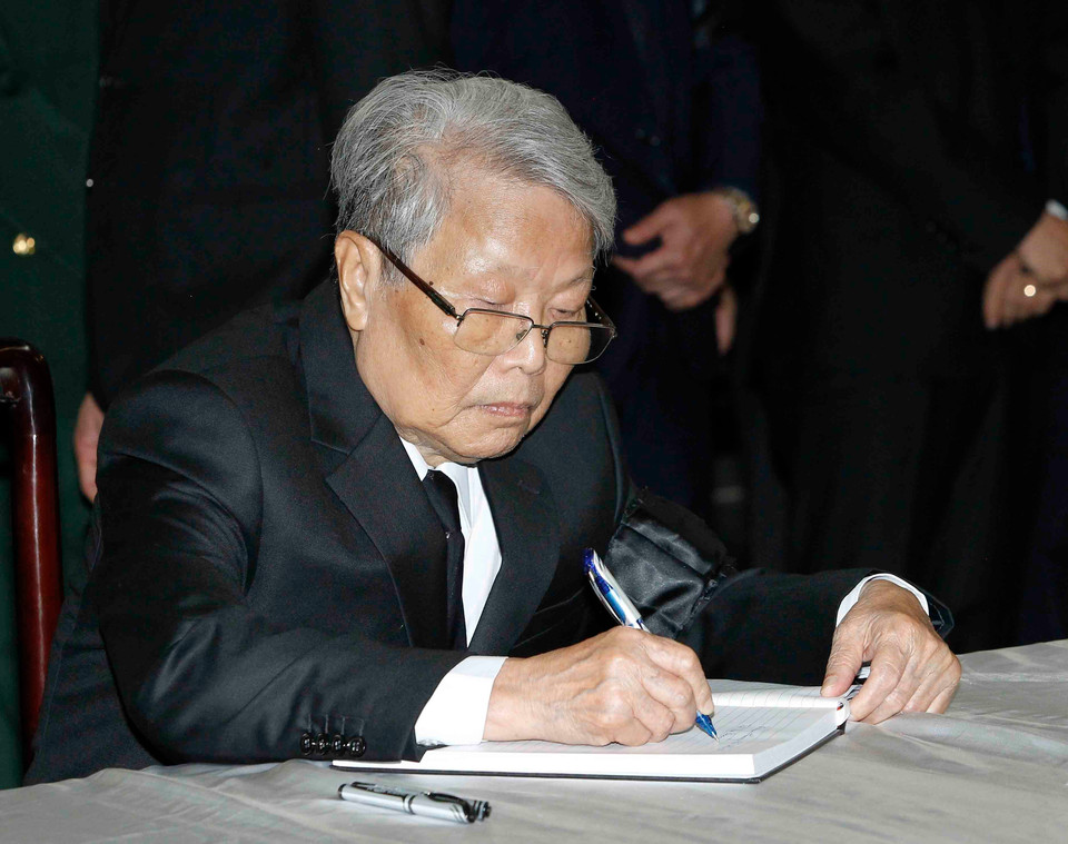前越共中央政治局委员、原国家主席陈德良（左）在吊唁簿上留言。图自越通社