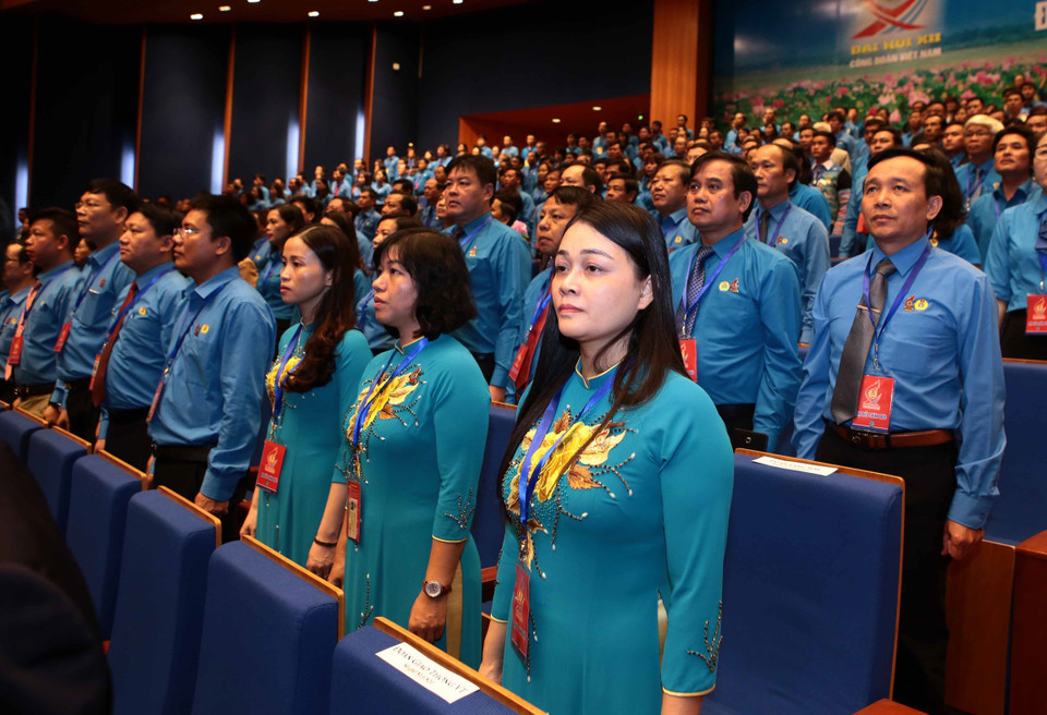 与会代表向国旗敬礼。 图自越通社