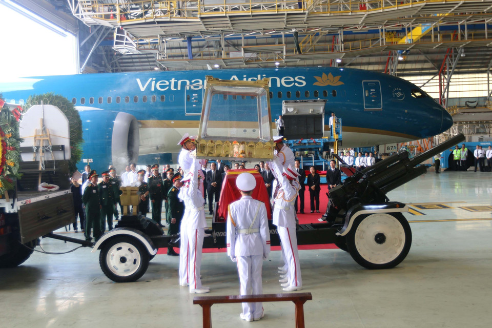 护灵的军人仪仗队将灵柩从飞机搬下来,送入等候在一边的灵车。图自越通社
