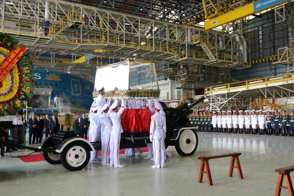 护灵的军人仪仗队将灵柩从飞机搬下来,送入等候在一边的灵车。图自越通社