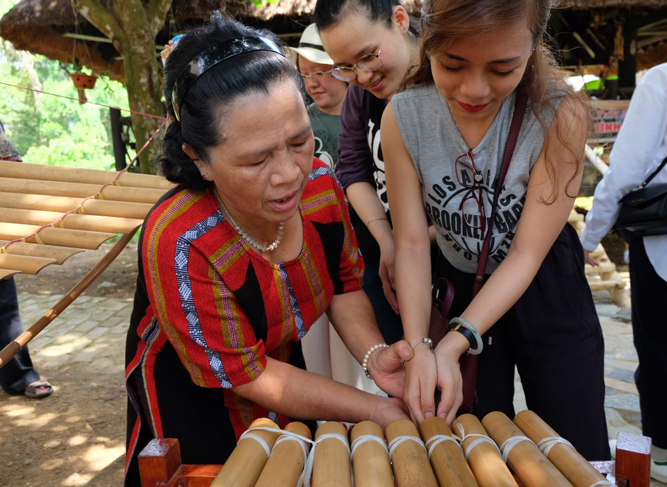 色当族艺人依生引导年轻游客们演奏哥龙瀑特琴。图自越通社
