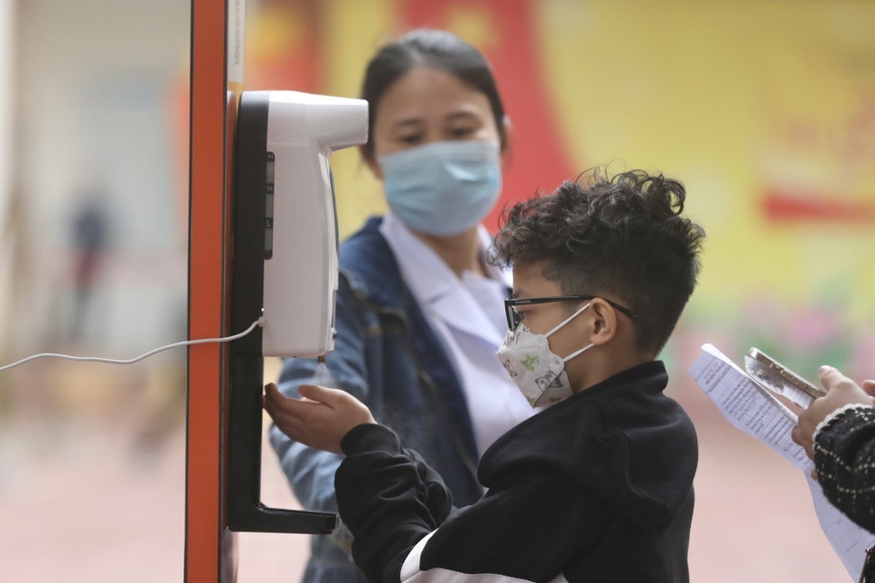 接种之前，学生及其家属接受测量体温和洗手杀菌。图自越通社