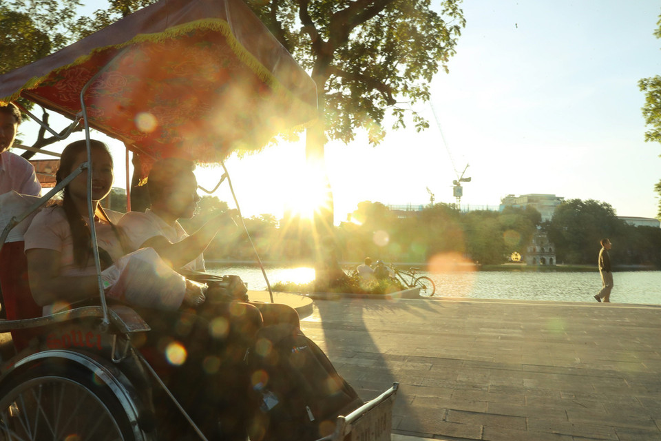 秋天来到河内时，游客可乘坐三轮车游览河内古街，欣赏还剑湖美景。图自 越通社