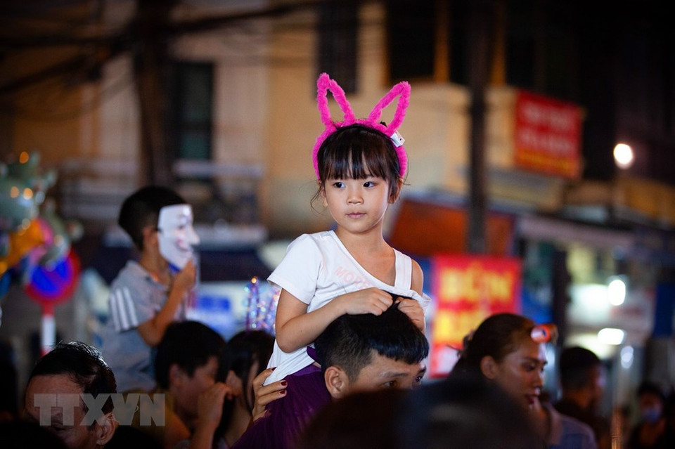 小女孩坐在爸爸肩膀上游街。越通社记者 明公 摄