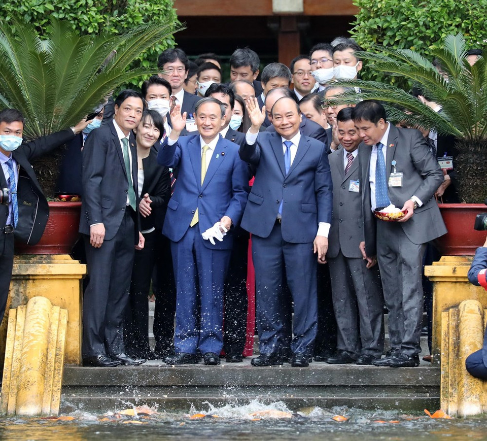 日本首相菅义伟同越南政府总理阮春福在主席府胡志明主席遗迹区的胡伯伯鱼塘喂鱼。越通社记者统一 摄