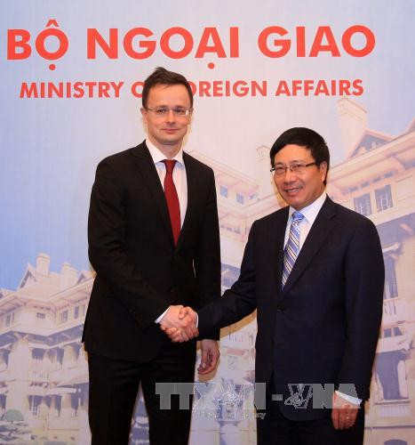  越南政府副总理兼外长范平明迎接彼得·西亚尔托部长。（图片来源：越通社）