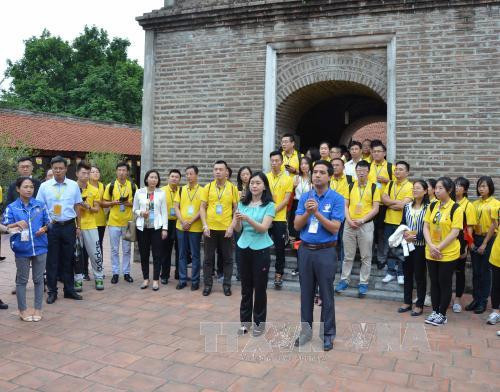 中国青年倾听导游介绍桑寺的历史和相关内容（图片来源：越通社）