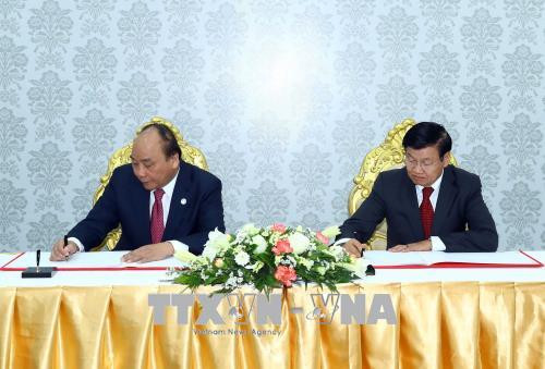 越南政府总理阮春福（左）与老挝政府总理通伦·西苏里在纪念薄上留言。越通社记者 统一 摄