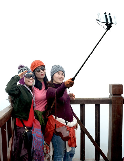 游客在番西邦峰上云雾中合影留念（图片来源：人民军队报）