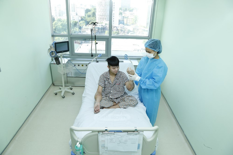 医生引导病人恢复双手运动功能。图自越通社