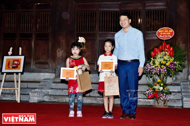  文庙文化科学中心主任黎春骁向获得“金黄民间绘画创意”竞赛的儿童颁奖。图自《越南画报》