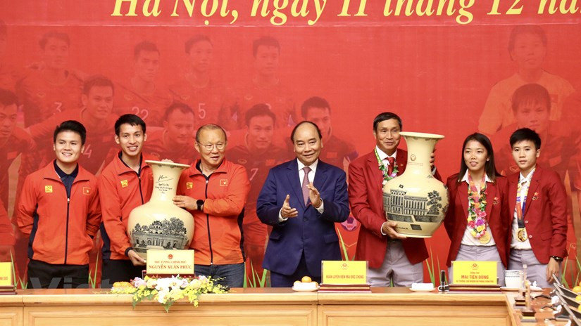 阮春福总理向刚荣获第30届东运会金牌的越南男女足球队赠送瓷瓶。越通社记者 原安 摄
