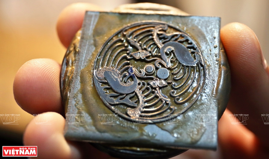 在涂上一层黄金的铁表盘上雕刻。《越南画报》记者 功达 摄