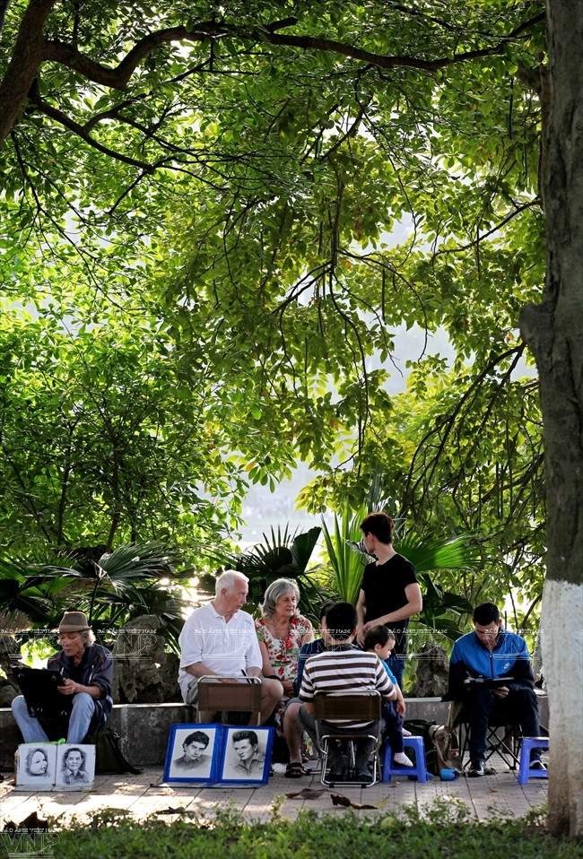 画家在树荫下画画儿。（图片来源：越通社《越南画报》）