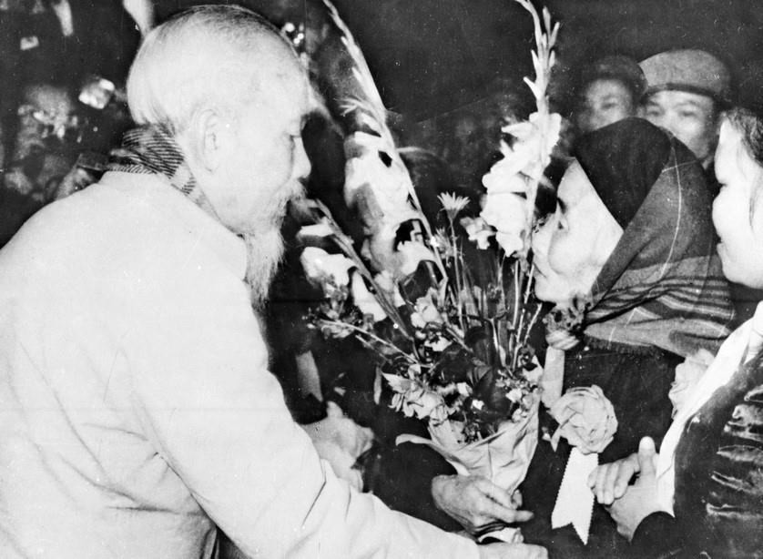 在1966年第四届全国英雄战士竞赛大会上，胡主席向身为高平省6名部队母亲的陶氏粉送花。图自越通社