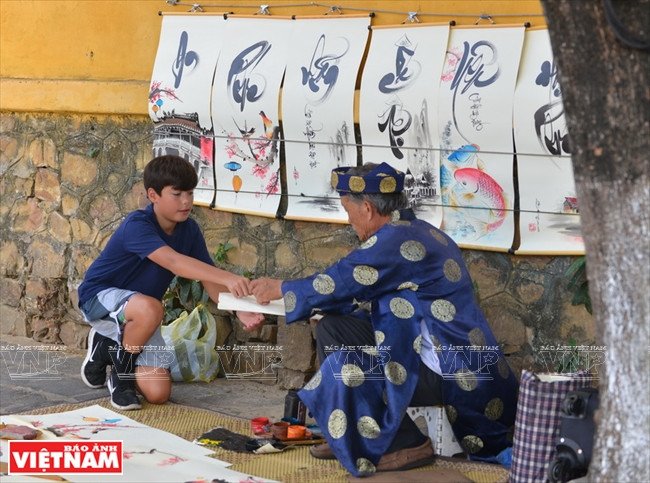 外国小朋友在会安街道向书法家求字。本报记者 清和 摄