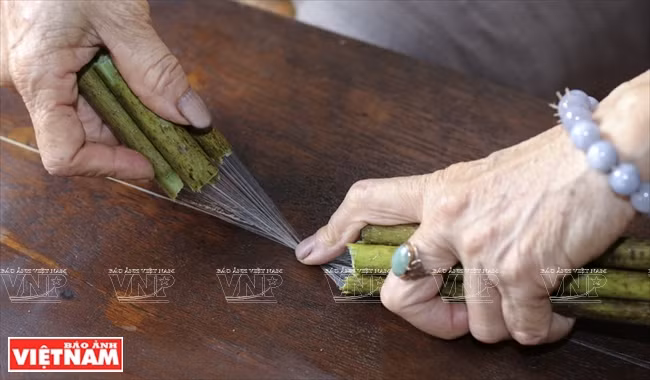 把数根莲茎的丝搓成纱才能编织。越南画报记者 越强