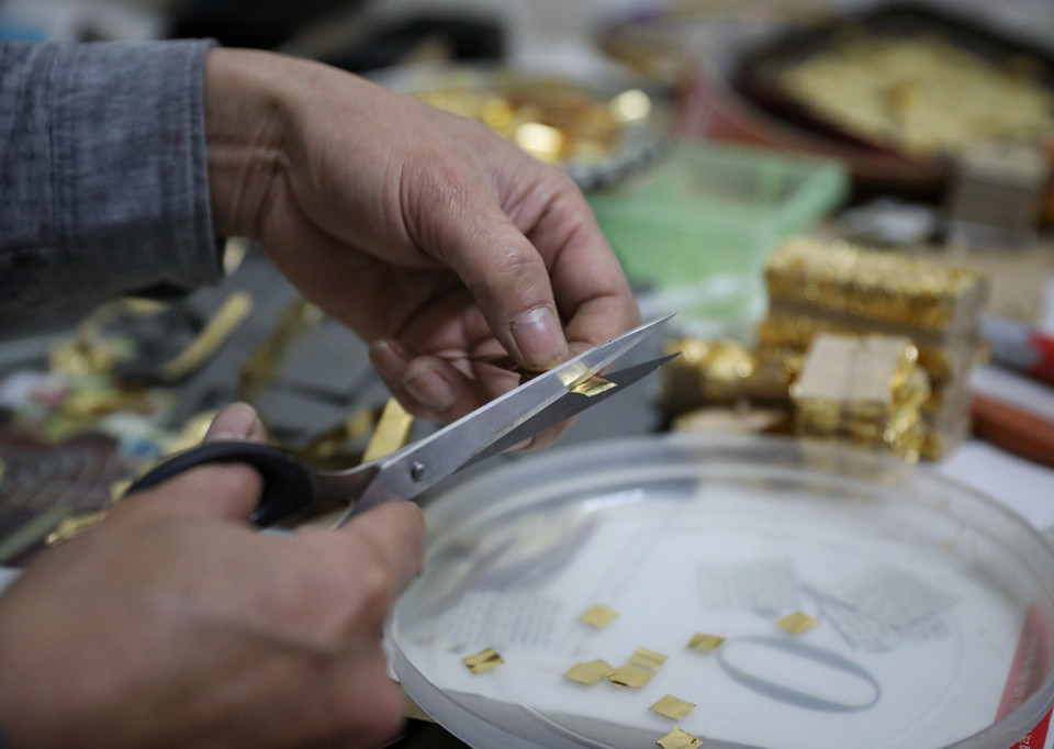 艺人把金片敲成薄片并剪成1厘米长的正方形。图自越通社