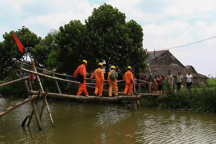 南电工超越独木桥为西南部区高棉族人输电线。越南画报记者 阮玉俊 摄